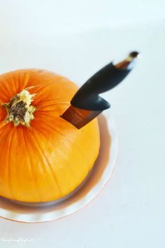 an orange pumpkin sitting on top of a white plate next to a black marker and pen