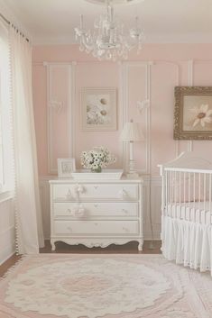 a baby's room with pink walls, white crib and chandelier