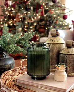 a christmas tree is in the background with books and vases sitting on a table