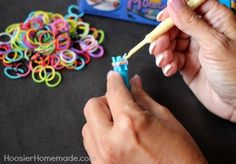 a person holding a toothbrush in their hand next to some colorful bracelets on the table