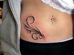 a woman's stomach with a tattoo design on the side and an earring