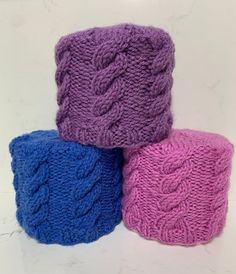 three different colored knitted items sitting on top of each other