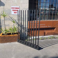 a metal gate with signs on it near a planter filled with succulents