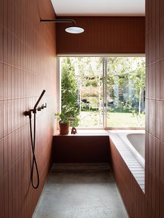 a bath room with a tub a window and a shower head mounted to the wall