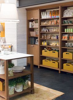 a kitchen with lots of wooden shelves and yellow bins on the floor next to it