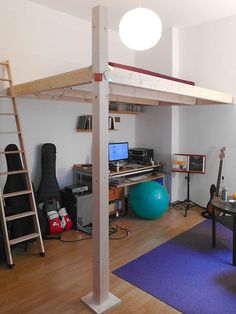 a living room with a loft bed, desk and computer on top of the table