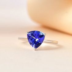 a tan and white ring with a blue heart shaped gemstone on the side, sitting on a table