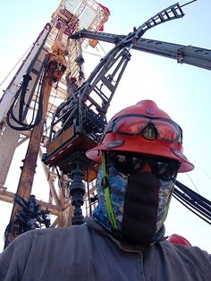 a man wearing a helmet and goggles standing in front of a crane