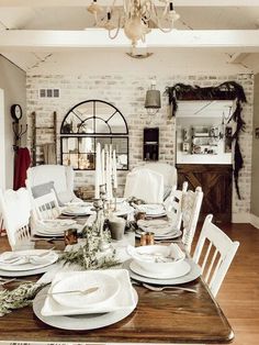 the dining room table is set with white plates and place settings