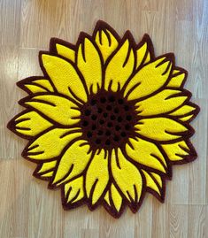 a yellow and brown rug with a large sunflower on the floor in front of it