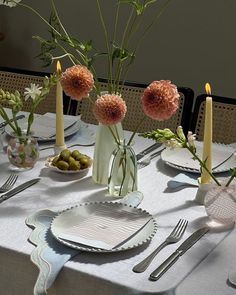 the table is set with plates, silverware and vases filled with pink flowers