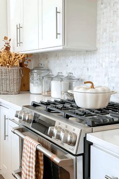 a kitchen with white cabinets and stainless steel stove top oven, dishwasher and utensils on the counter