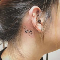 a woman's ear with an arrow tattoo on her left side behind the ear