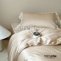 a bed with two pillows and a pillow case on top of it next to a lamp