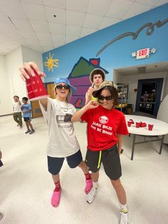 two young boys are holding up their hands in front of the camera, while another boy is wearing sunglasses and a red t - shirt