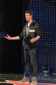 a man standing on top of a stage with his hands out to the side while talking