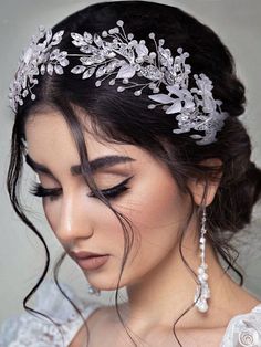 a woman wearing a bridal headpiece with pearls and leaves on the top of it