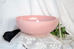 a pink bowl sitting on top of a table next to a white lace doily