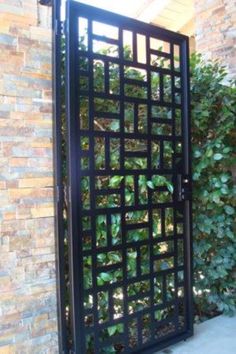 an iron gate in front of a brick wall with green plants growing on the side