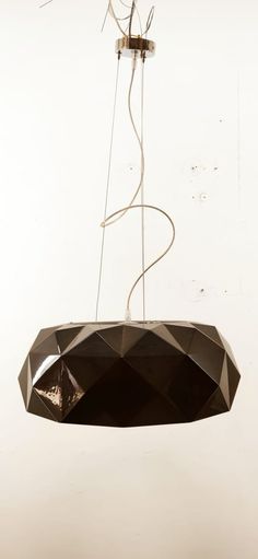 a light hanging from a ceiling with wires attached to it's sides and an object in the background