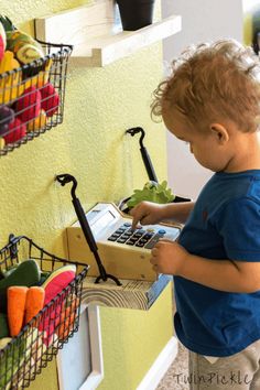 a little boy that is standing in front of a shelf with some fruit and vegetables