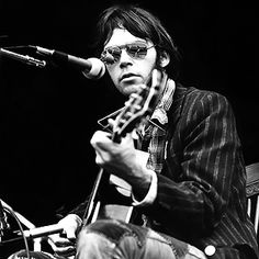 a man sitting in front of a microphone while holding a guitar