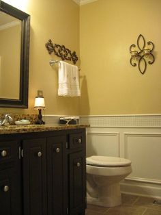 a white toilet sitting next to a sink in a bathroom under a mirror and light