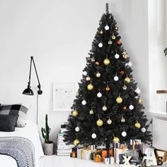 a black christmas tree with gold and white ornaments in a bedroom decorated for the holidays