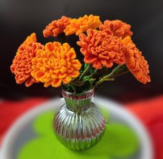 an orange flower in a glass vase on a green and white tableclothed surface