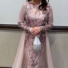 a woman in a long dress standing next to a wall with a purse on it