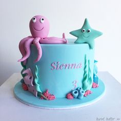 a blue cake with an octopus, starfish and seahorse on it's side