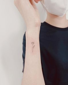 a woman wearing a face mask and holding her hand up to her ear with a single flower tattoo on it