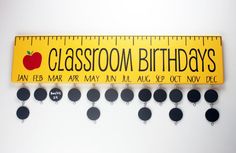 a yellow ruler with black circles and an apple on it that says classroom birthdays