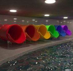 a row of colorful buckets sitting next to a swimming pool in a public restroom