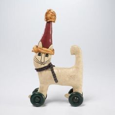 a white cat with a red hat and green wheels