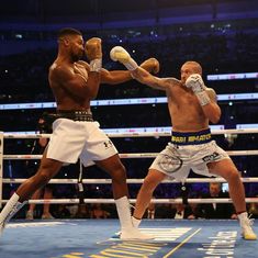 two men in the middle of a boxing match, one is hitting the other with his right hand