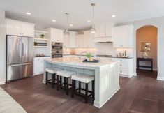 a large kitchen with an island in the middle and stools at the end,