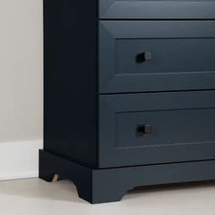 a black dresser with three drawers in the corner