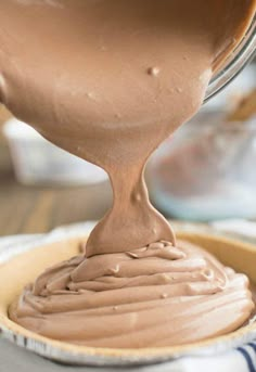 a person pouring chocolate frosting on top of a pie