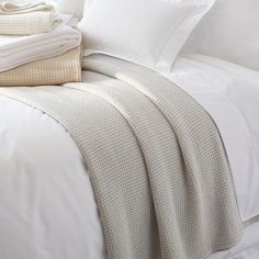 an unmade bed with white sheets and pillows