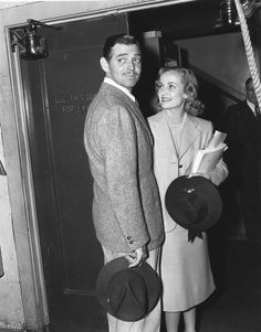 a man and woman standing next to each other in front of a door wearing hats