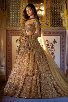 a woman in a gold gown standing next to a wall