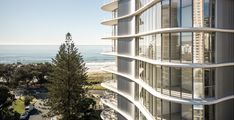 an apartment building overlooking the ocean with balconies on each floor and glass windows