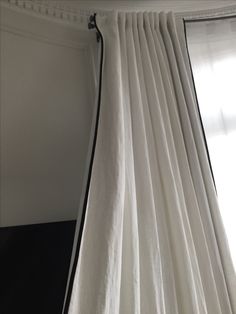 the curtain is pulled back to let light into the room with it's black and white drapes