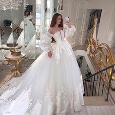 a woman in a white wedding dress taking a selfie with her cell phone while standing on stairs