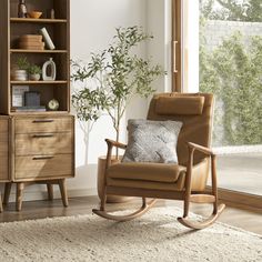 a rocking chair in front of a bookcase with plants on it and a window