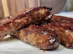 some very tasty looking meats on a white plate with brown stuff around them