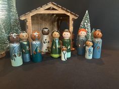 a group of wooden dolls standing in front of a nativity figurine set