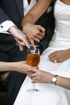 the bride and groom are holding their wine glasses for each other as they sit together