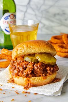 a sloppy joe sandwich sitting on top of a white napkin next to pretzels